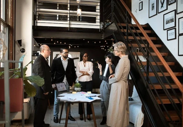 A team of business individuals gathered in front of a staircase